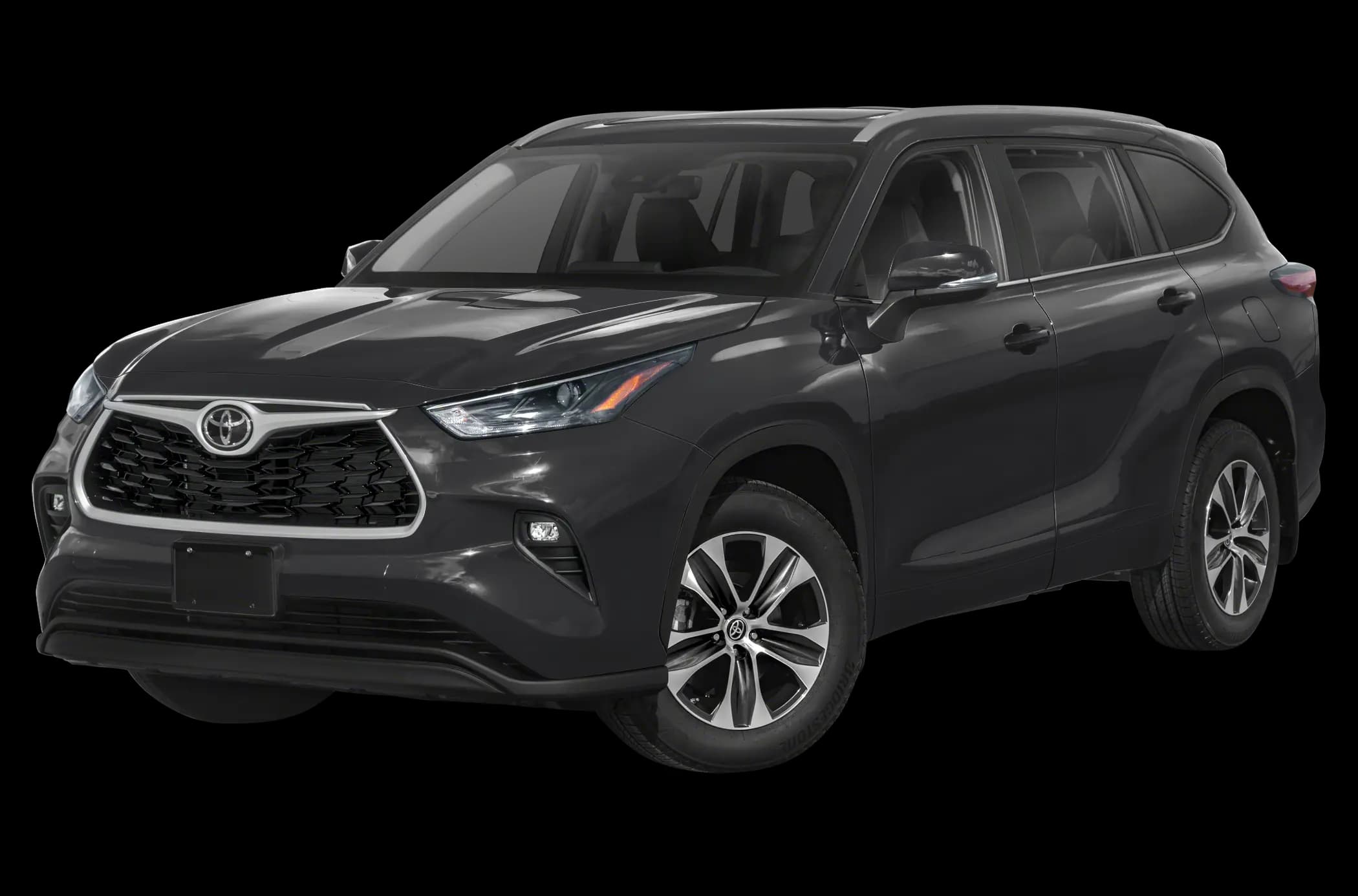 A dark gray Toyota Highlander SUV parked outside a modern glass building, showing the current-generation front and side styling