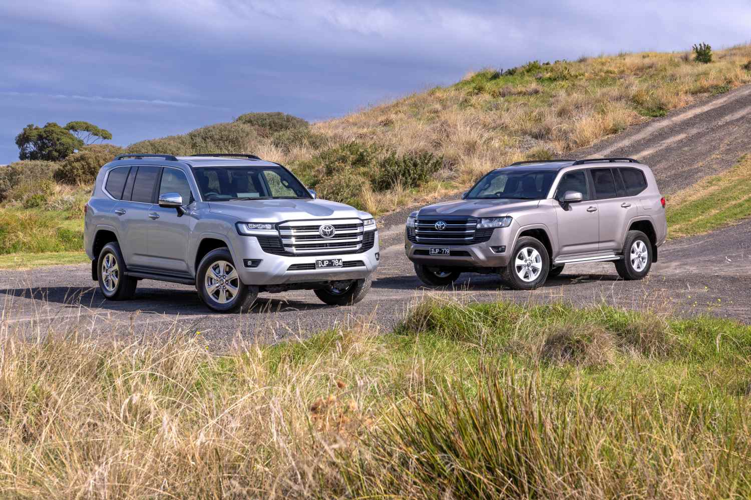 Two Toyota Land Cruiser 300 Series SUVs in different trims, silver and champagne