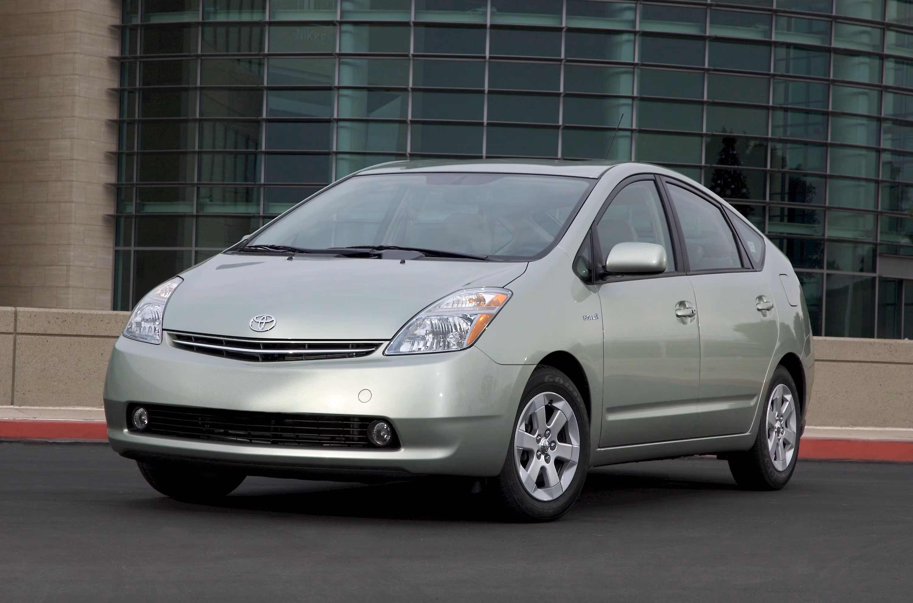 A second-generation Toyota Prius (NHW20) parked outside a modern glass building